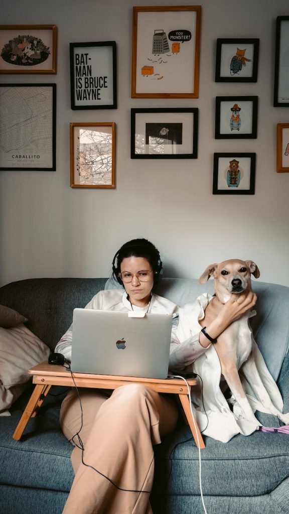 woman in white long sleeve shirt sitting on gray couch with macbook